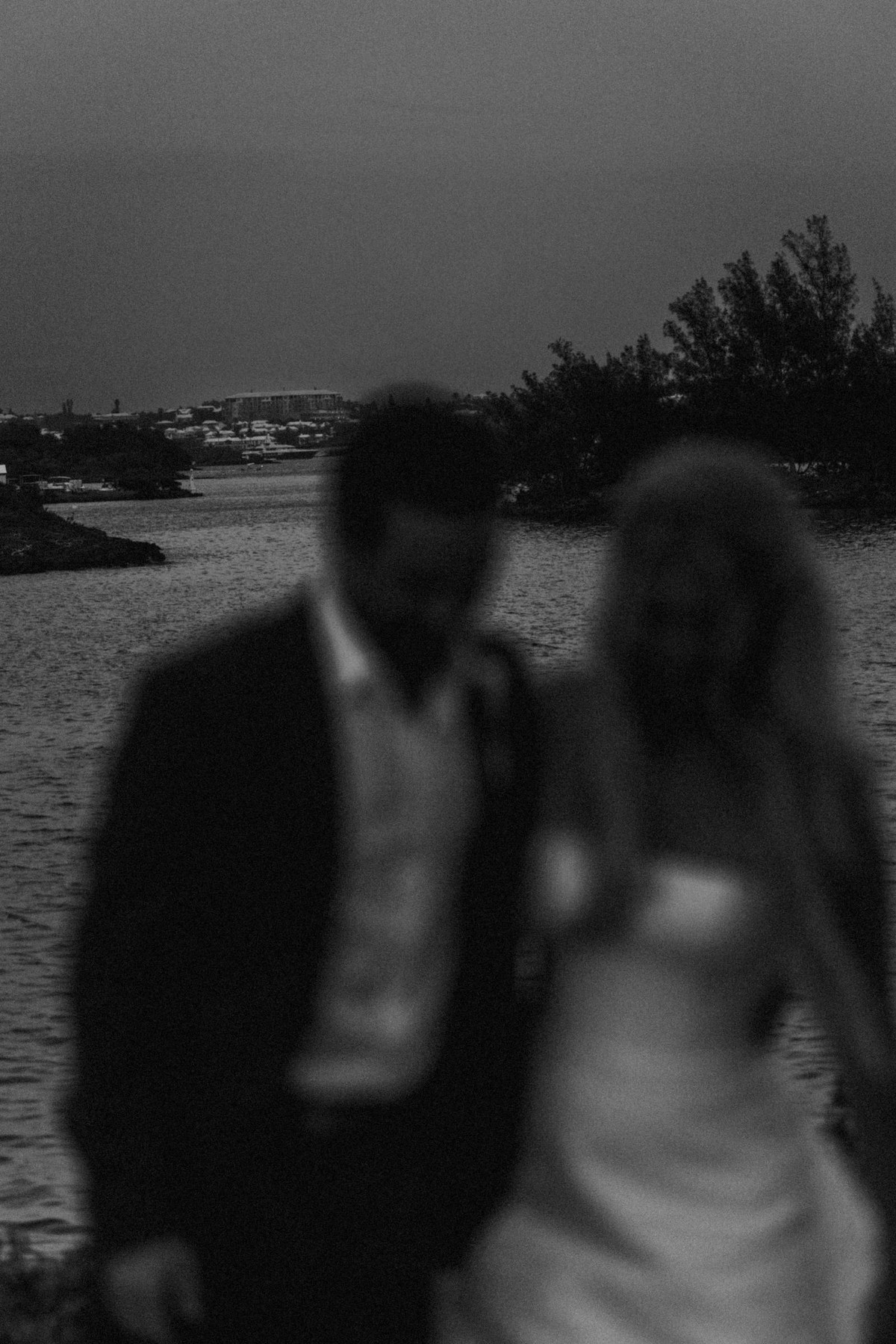Paige and Cam blur past the water at dusk in a moody black and white frame