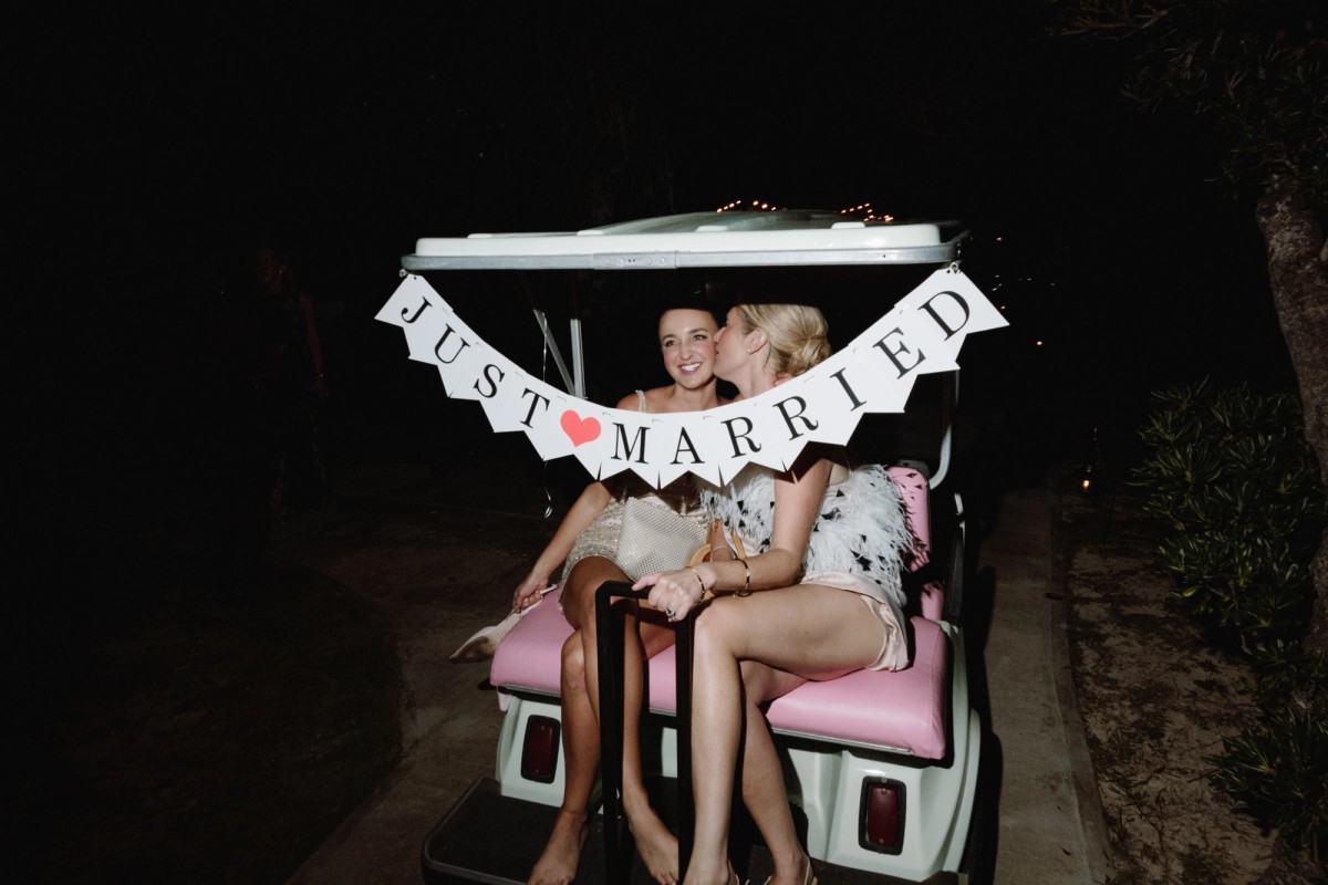 Two brides on a golf cart with a just married banner after their Bermuda wedding