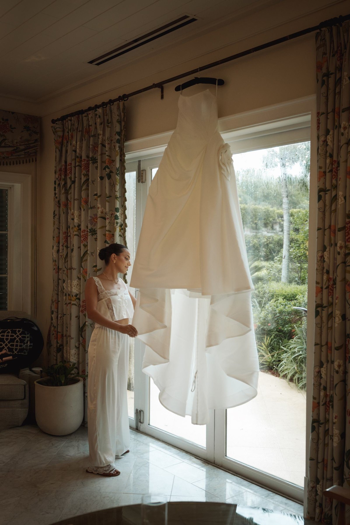 Bride looking at her gown hanging in the window of the suite at Rosewood Bermuda