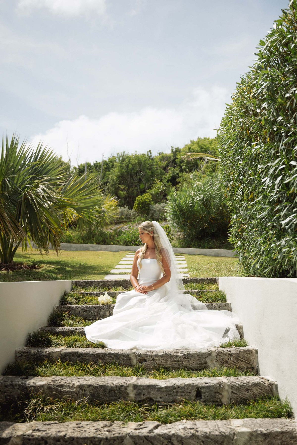 Paige sits on the grassy garden steps in her gown on Hawkins Island, Bermuda