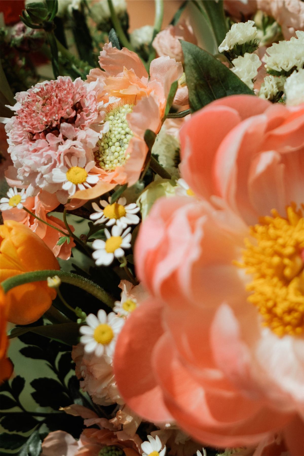 Close detail of the bouquet, coral peonies and daisies packed together