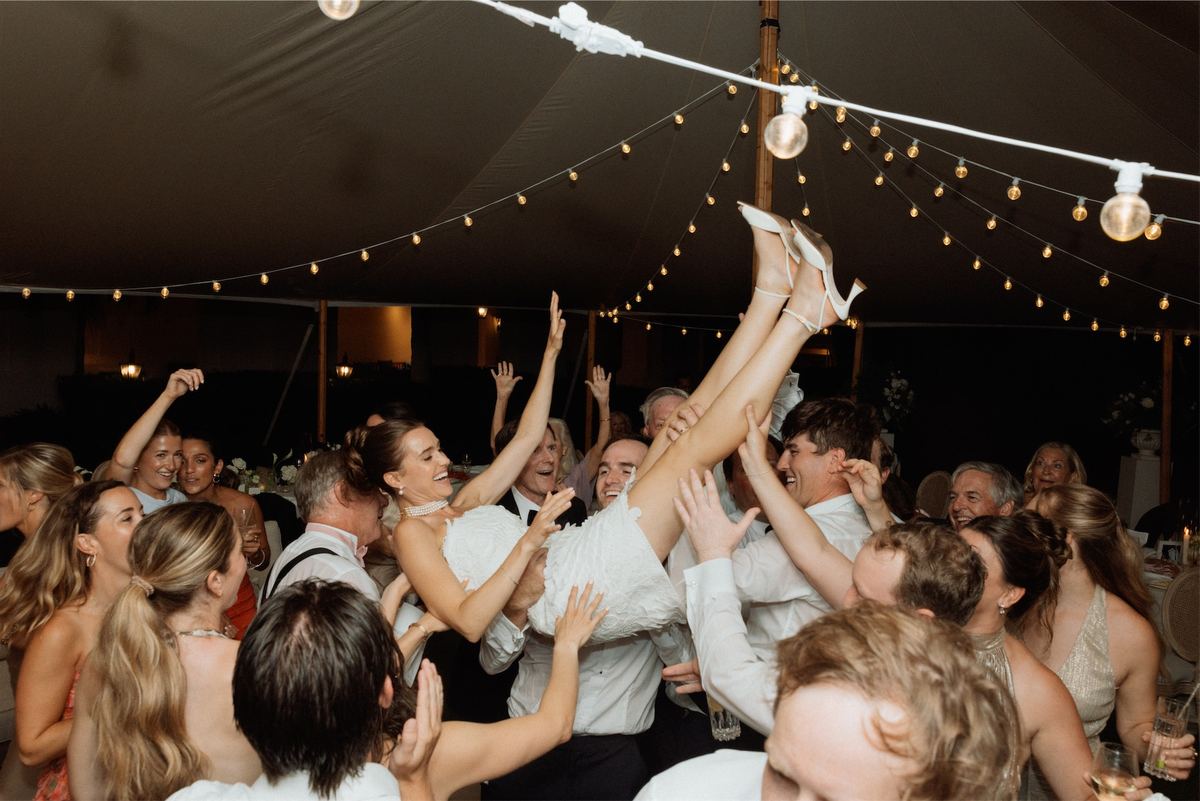 Guests lifting a friend overhead on the packed dance floor under the tent