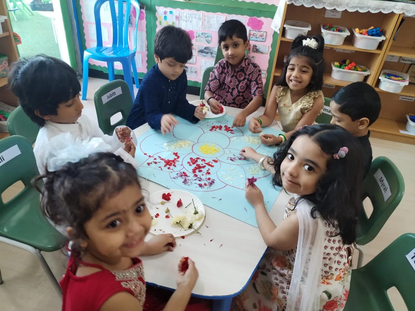 Children creating a colourful flower-petal design together around a classroom table