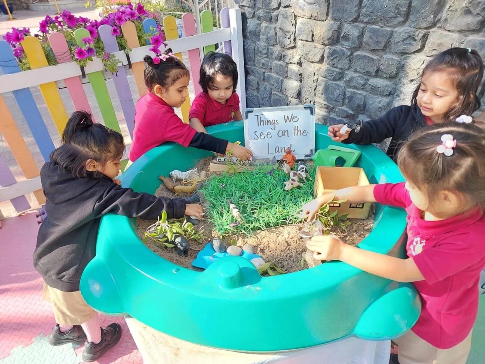 Children exploring plants and materials in a small-world tray