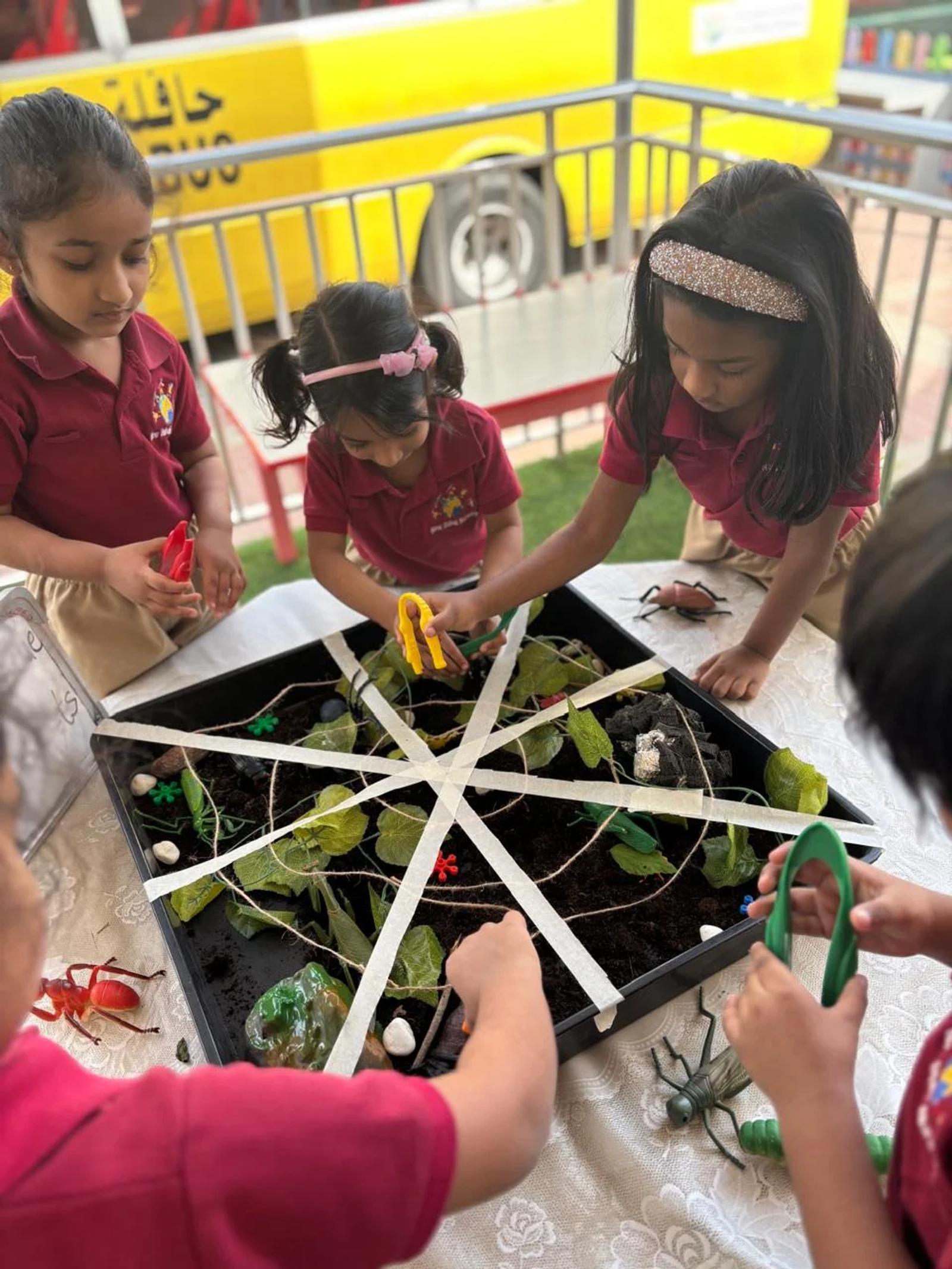 Children using tongs together to explore a sensory tray