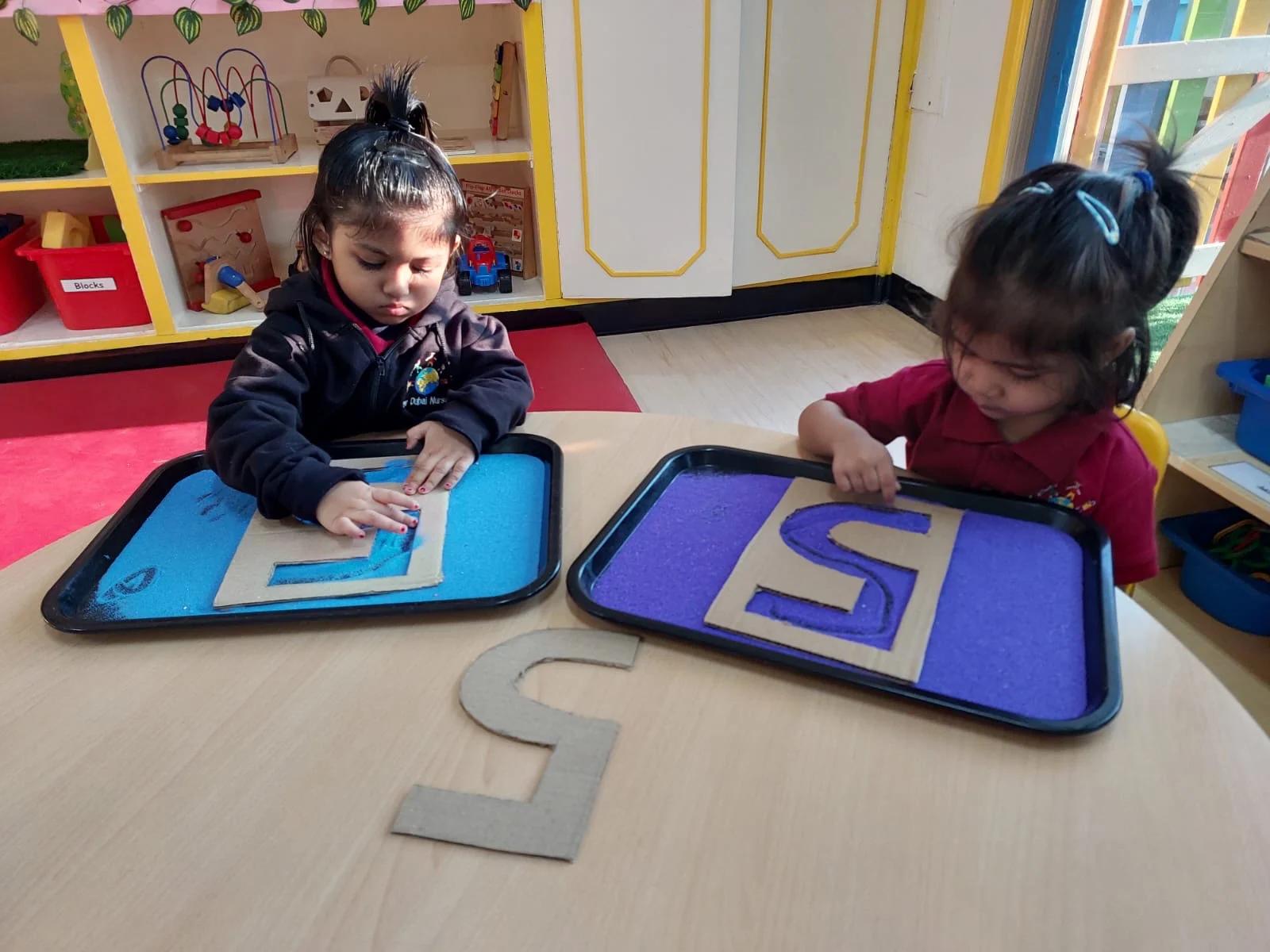 Children tracing number shapes in sensory trays
