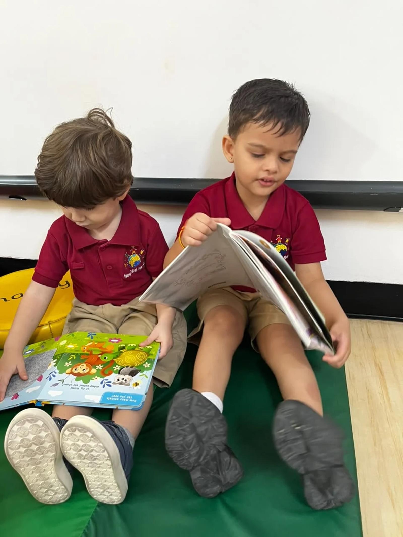 Two children enjoying picture books in the reading corner