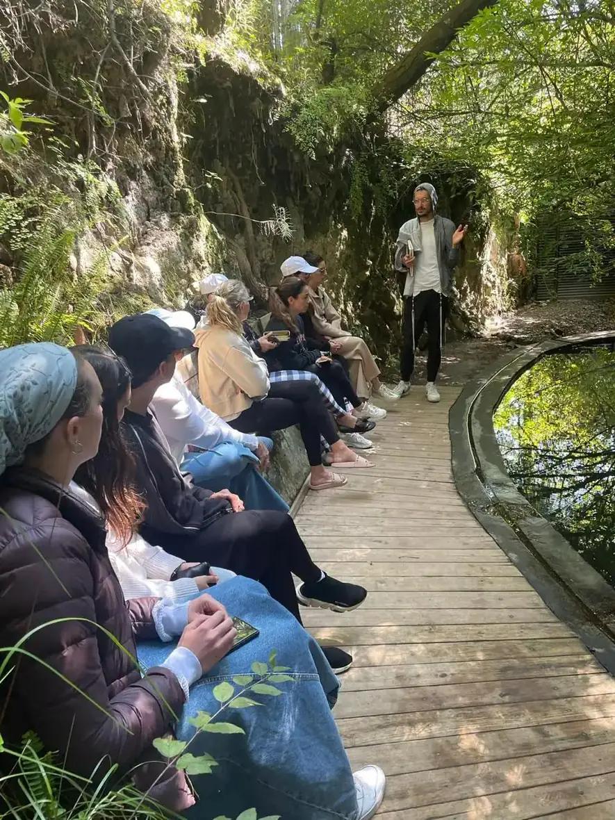 A guided cold plunge session at Attesi, with participants seated on the wooden boardwalk beside the spring