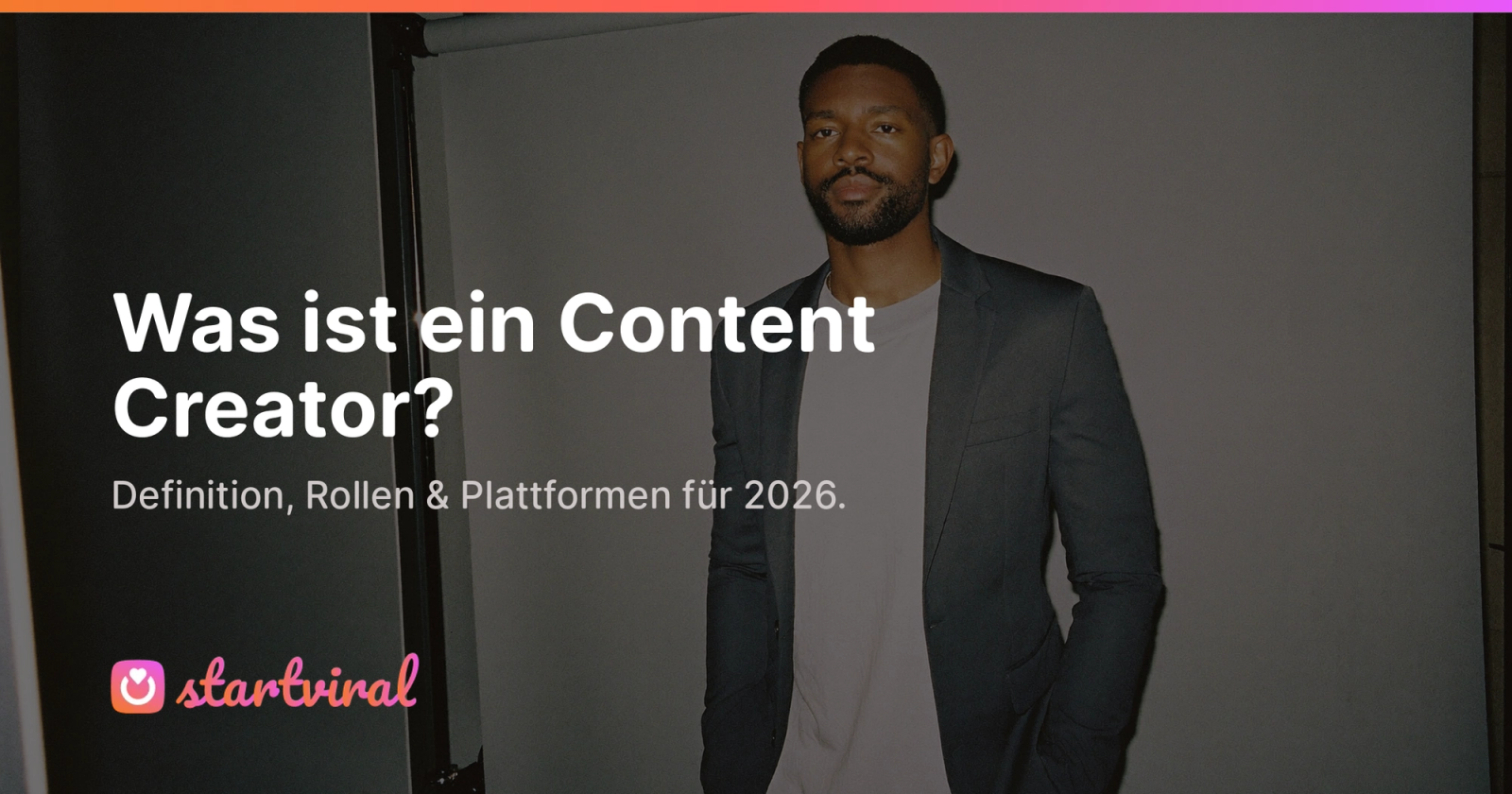 Mann in dunklem Blazer steht in einer Studiotür und blickt unter hartem Blitzlicht in die Kamera.