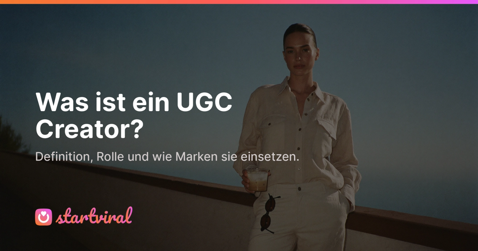 Frau in weißem Leinenhemd auf einer Terrasse am Meer in der Abenddämmerung.
