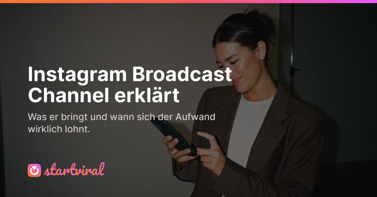 Frau im Blazer steht in einem Fotostudio und tippt lächelnd eine Nachricht auf ihrem Smartphone.