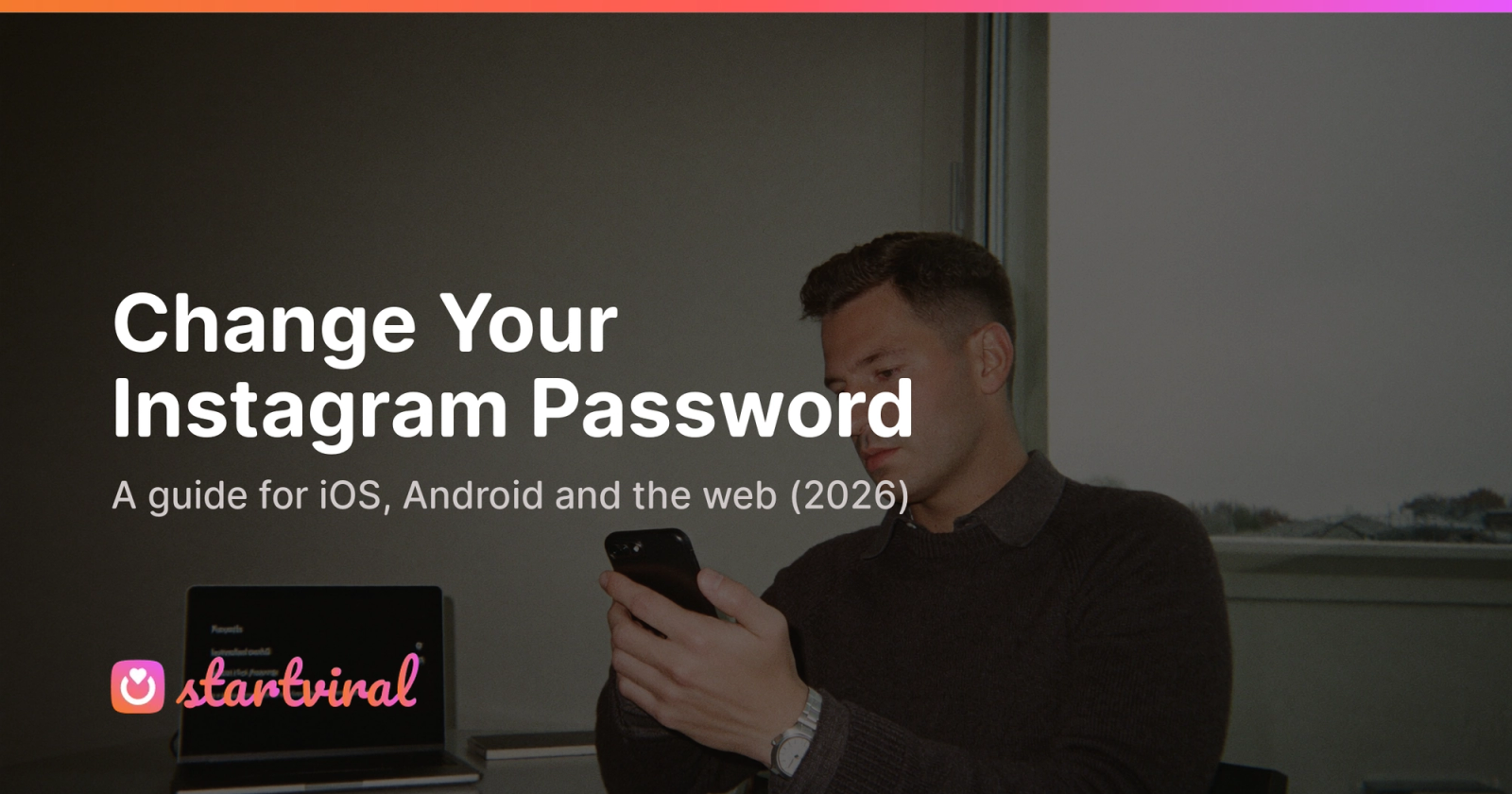 Man in a charcoal sweater sits at a desk, calmly typing a new password on his phone.