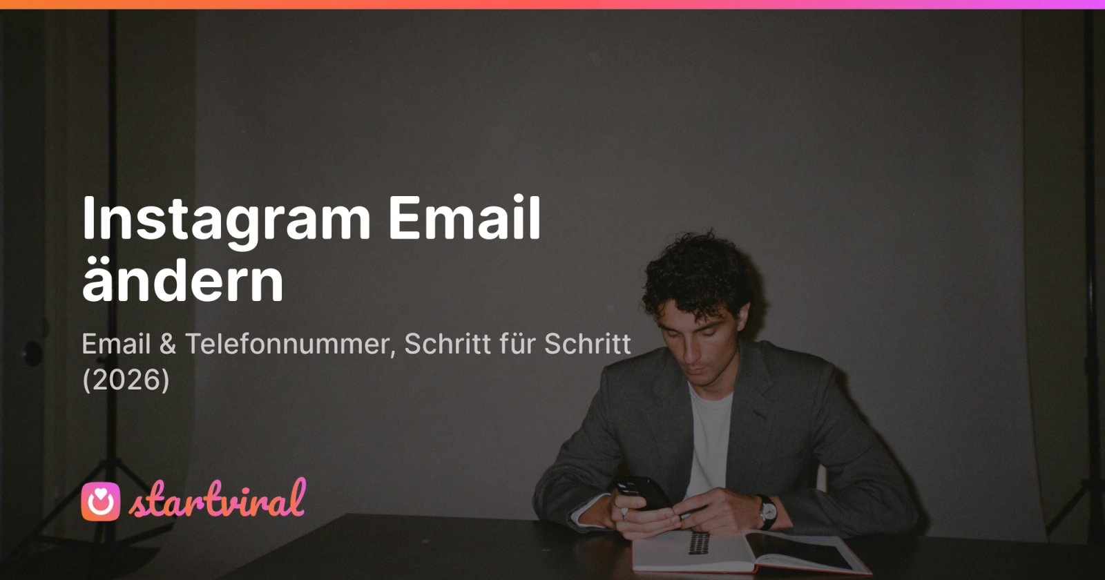 Mann sitzt an einem Schreibtisch vor einer Studio-Kulisse und bestätigt einen Code auf seinem Smartphone.