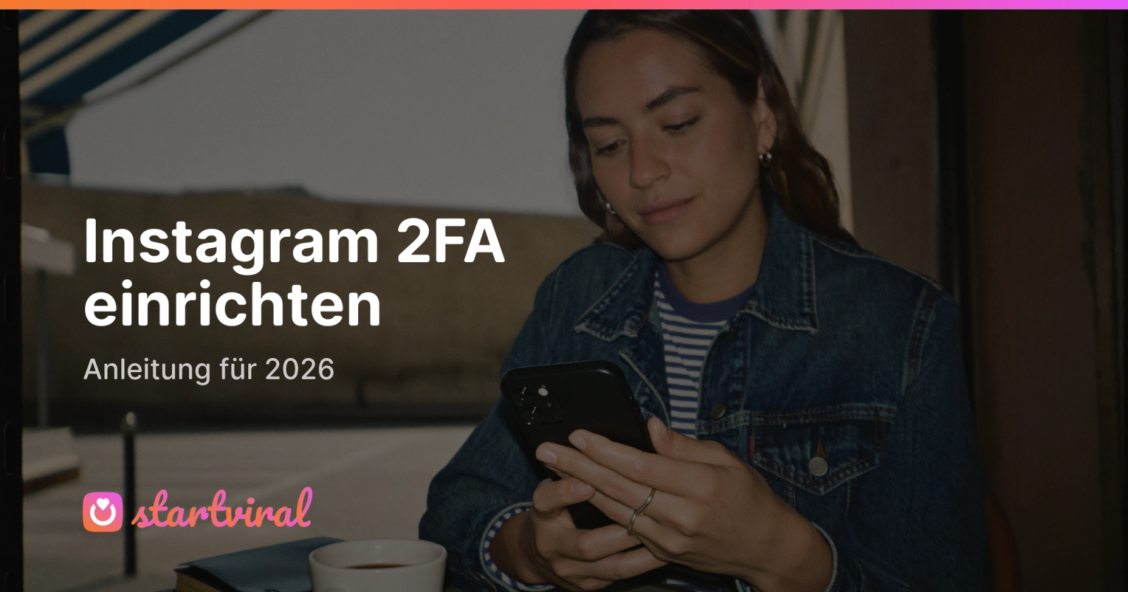 Frau in Jeansjacke sitzt an einem Cafétisch und gibt einen Code auf ihrem Smartphone ein.