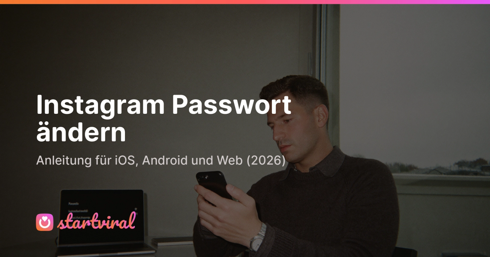 Mann in dunkelgrauem Pullover sitzt am Schreibtisch und tippt konzentriert ein neues Passwort auf seinem Smartphone.