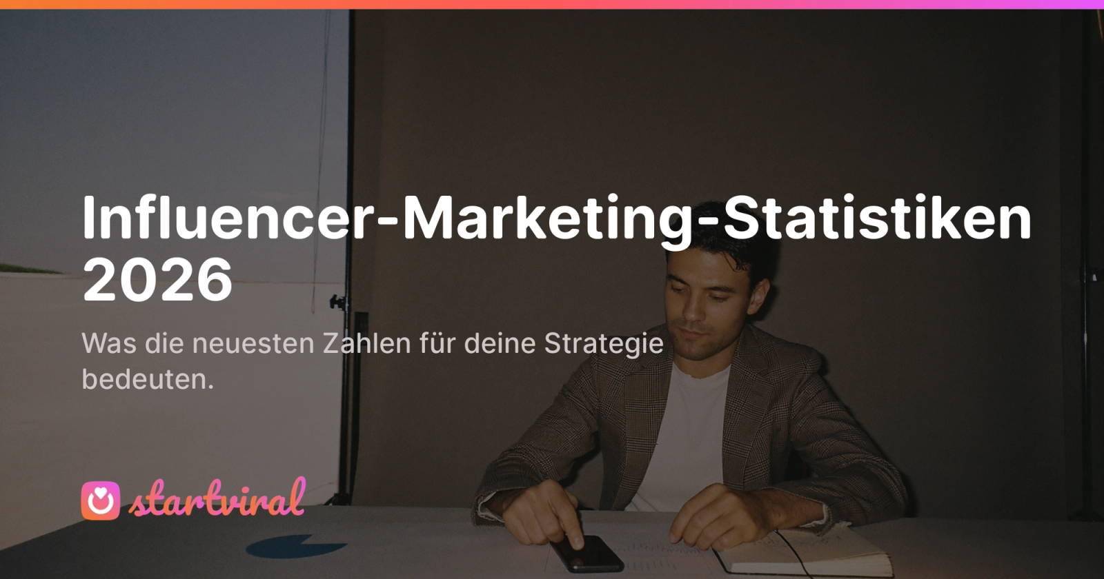 Mann sitzt an einem Tisch in einem Studio und schaut auf ein gedrucktes Diagramm und ein Notizbuch.