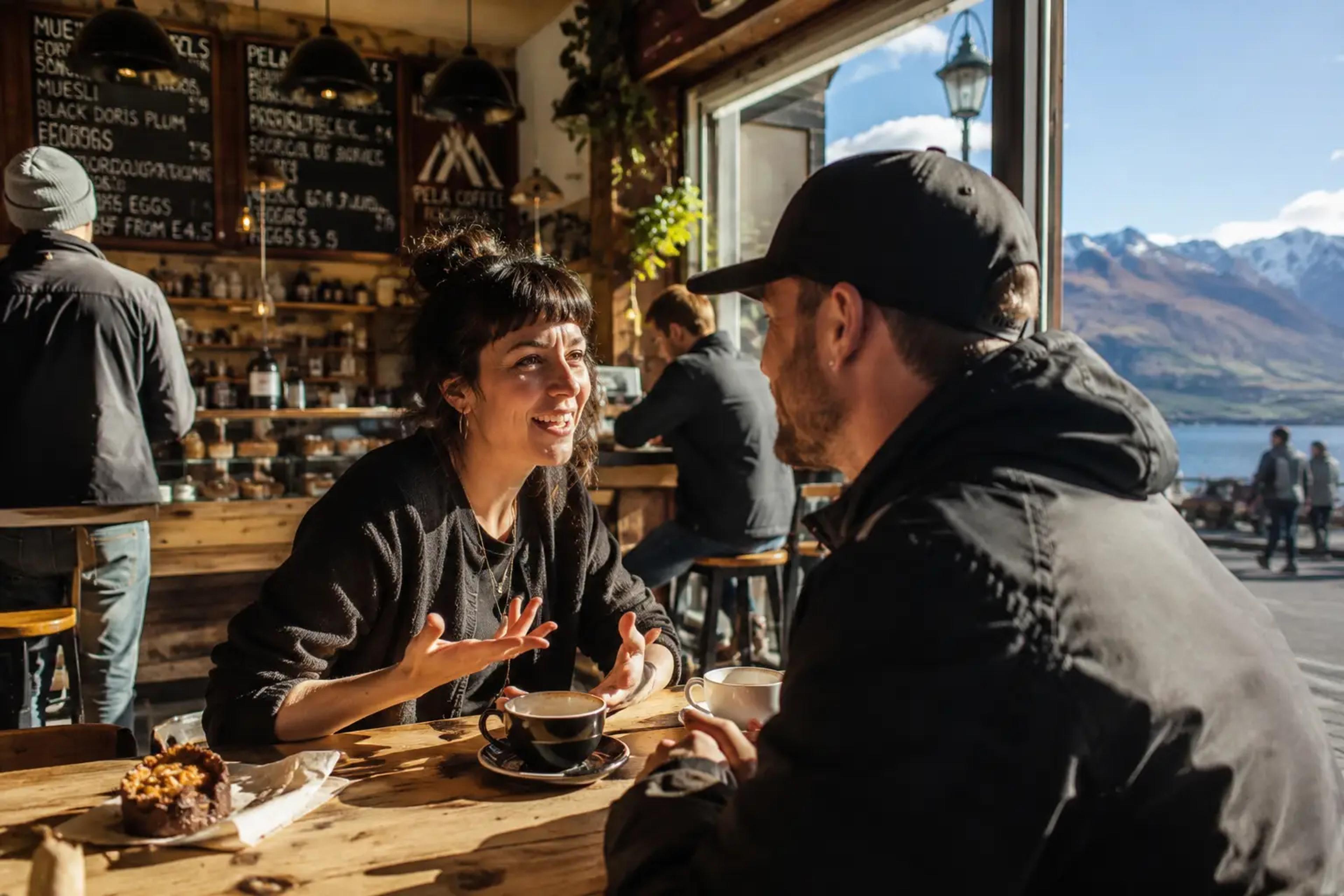 Two people talking over coffee in a Queenstown cafe