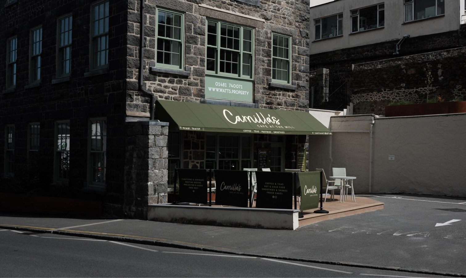 Camilla's Cafe, a stone building with a green awning and outdoor seating area.