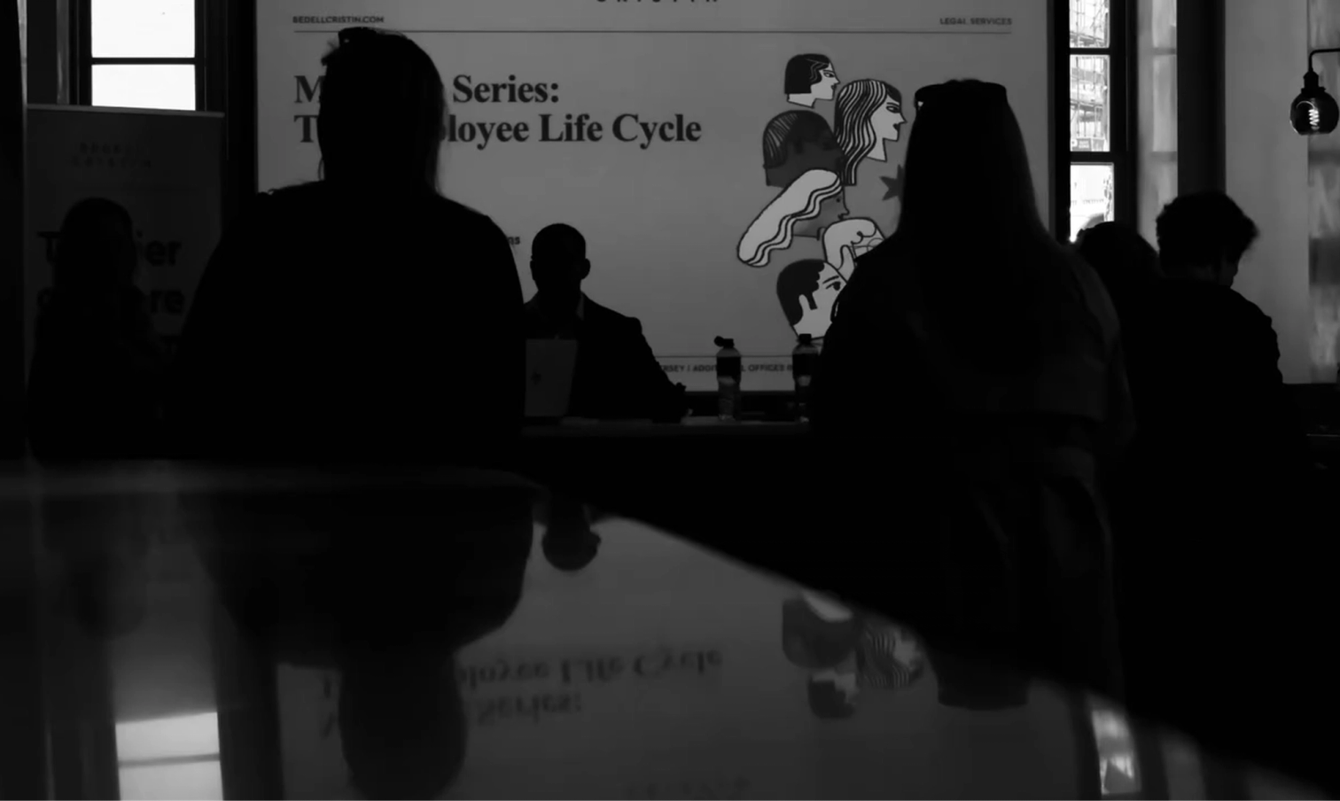 Black and white image of silhouetted attendees watching a presentation screen that reads "Series: The Employee Life Cycle" with illustrated faces.