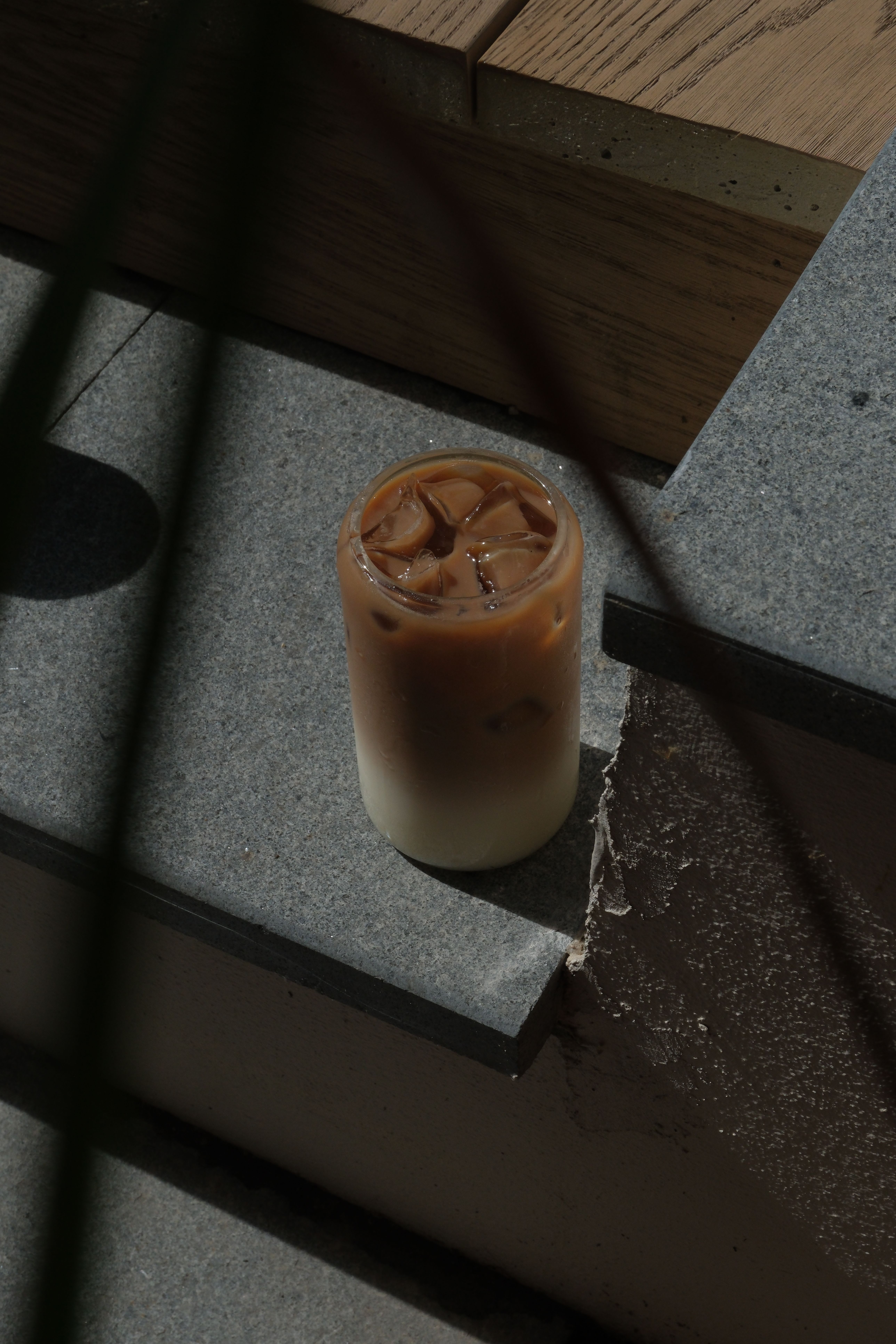 A glass of layered iced coffee on a dark gray surface.