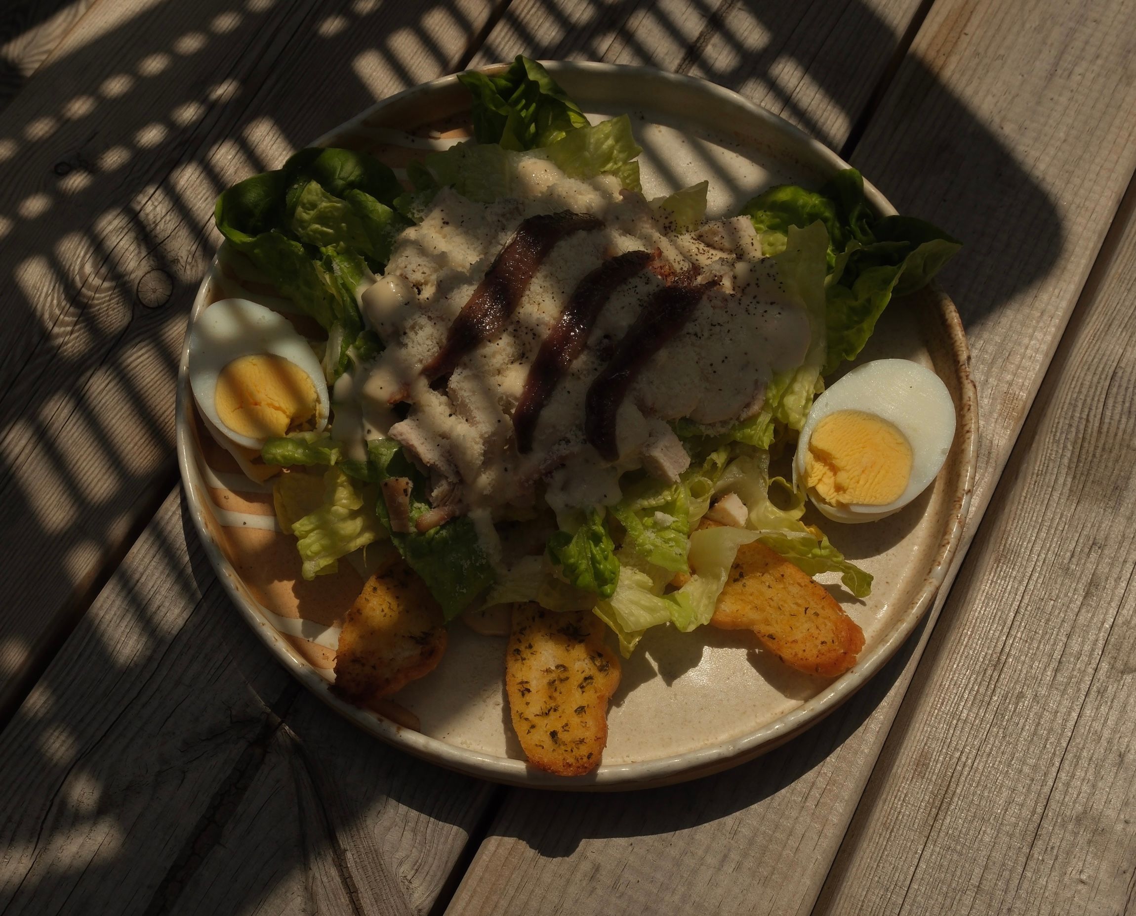 A chicken Caesar salad with bacon and dressing