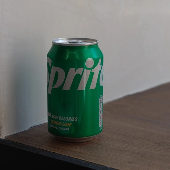 A green Sprite Low Calories lemon-lime can on a wooden surface.