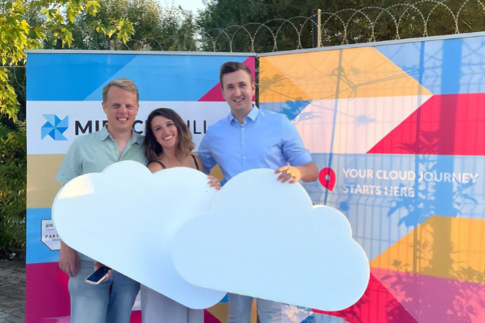 Smiling people holding styrofoam clouds in front of a Miracle Mill branded backdrop