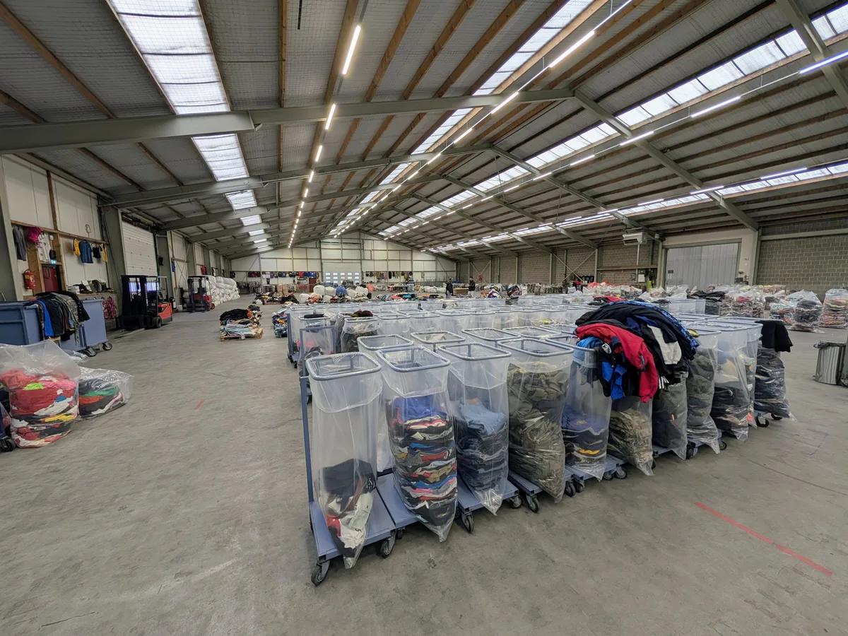 De magazijnvloer van Excellent Vintage met voorgesorteerde kleding balen op karren, klaar voor resellers in Bovenkarspel
