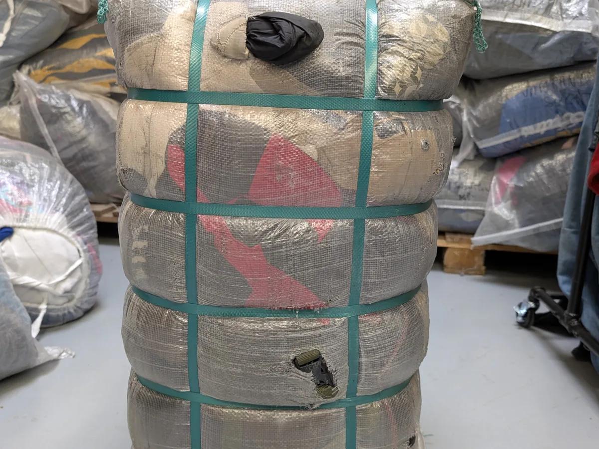 Geperste balen tweedehands kleding gestapeld per merk en grade in het Excellent Vintage warehouse in Bovenkarspel