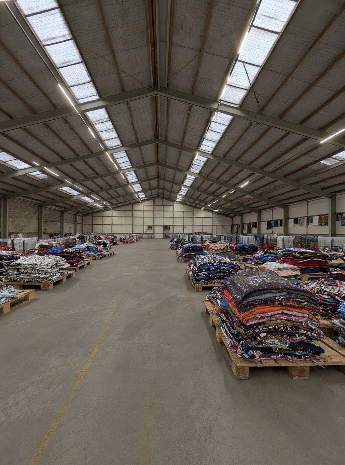 Overzicht van de balen-vloer bij Excellent Vintage met gesorteerde tweedehands kleding balen per merk en grade in Bovenkarspel