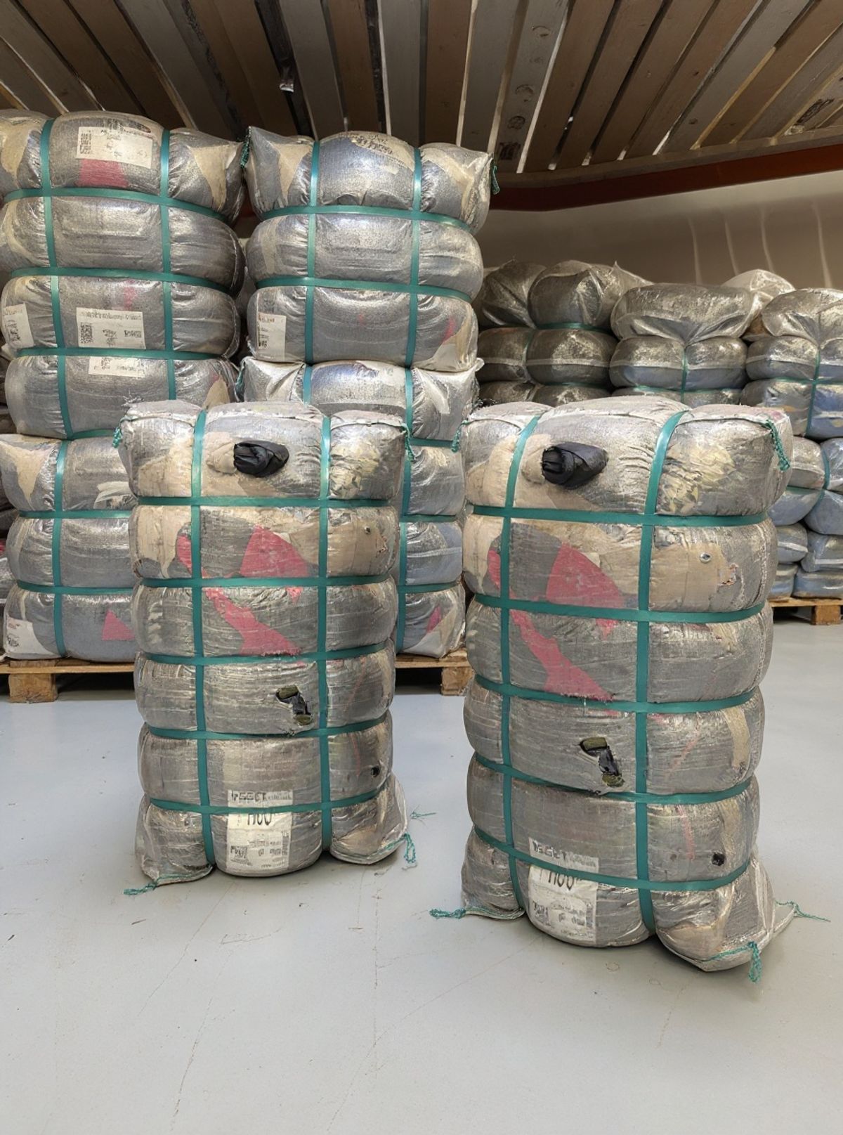 Vergelijking van een ongeopende heavy bale en gesorteerde tweedehands kledingstukken per merk in een vintage groothandel