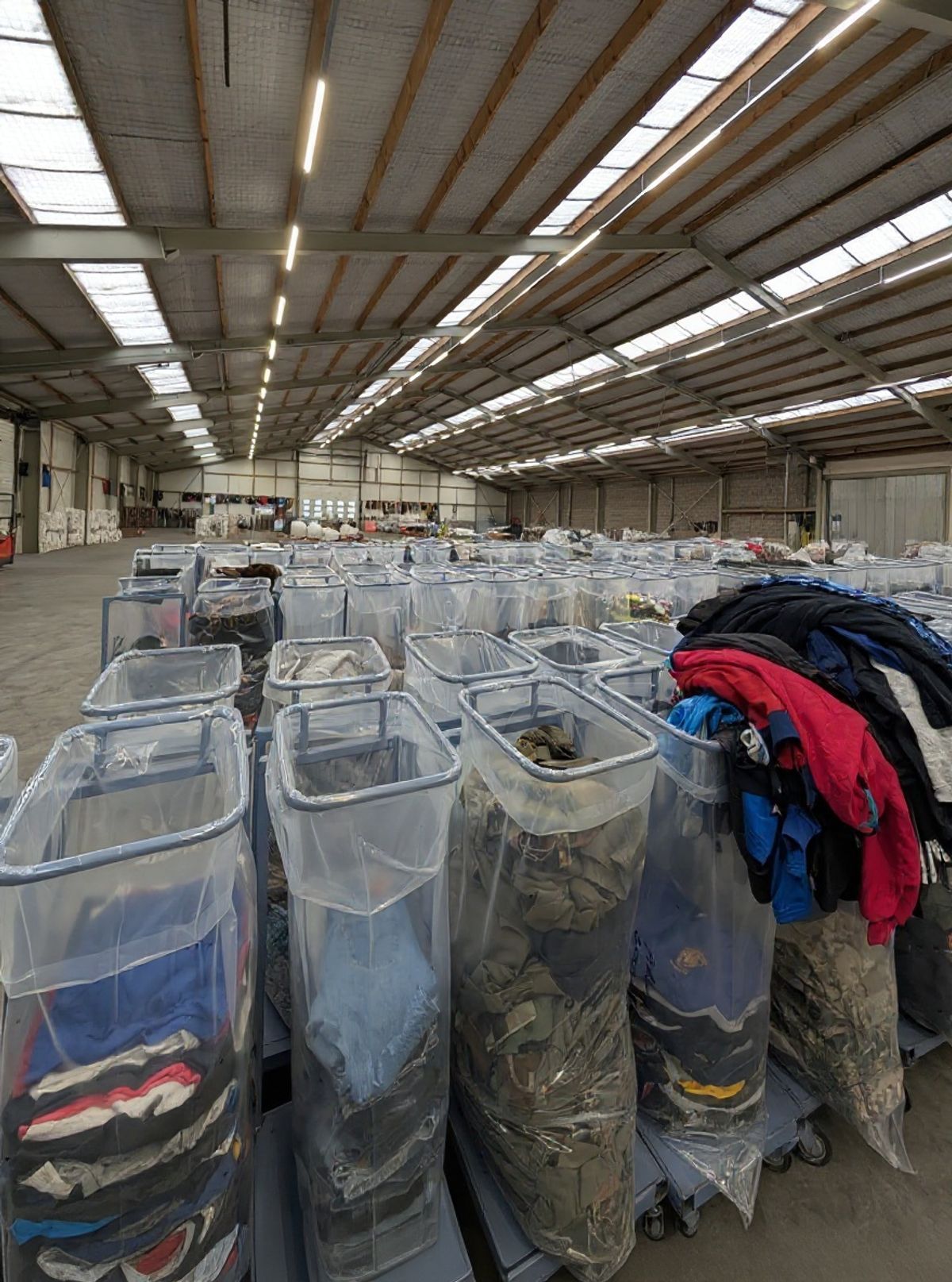 Gesorteerde tweedehands kleding in doorzichtige sorteerbakken op de warehousevloer van Excellent Vintage in Bovenkarspel