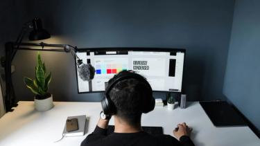 A man using a computer with a microphone to build a website.