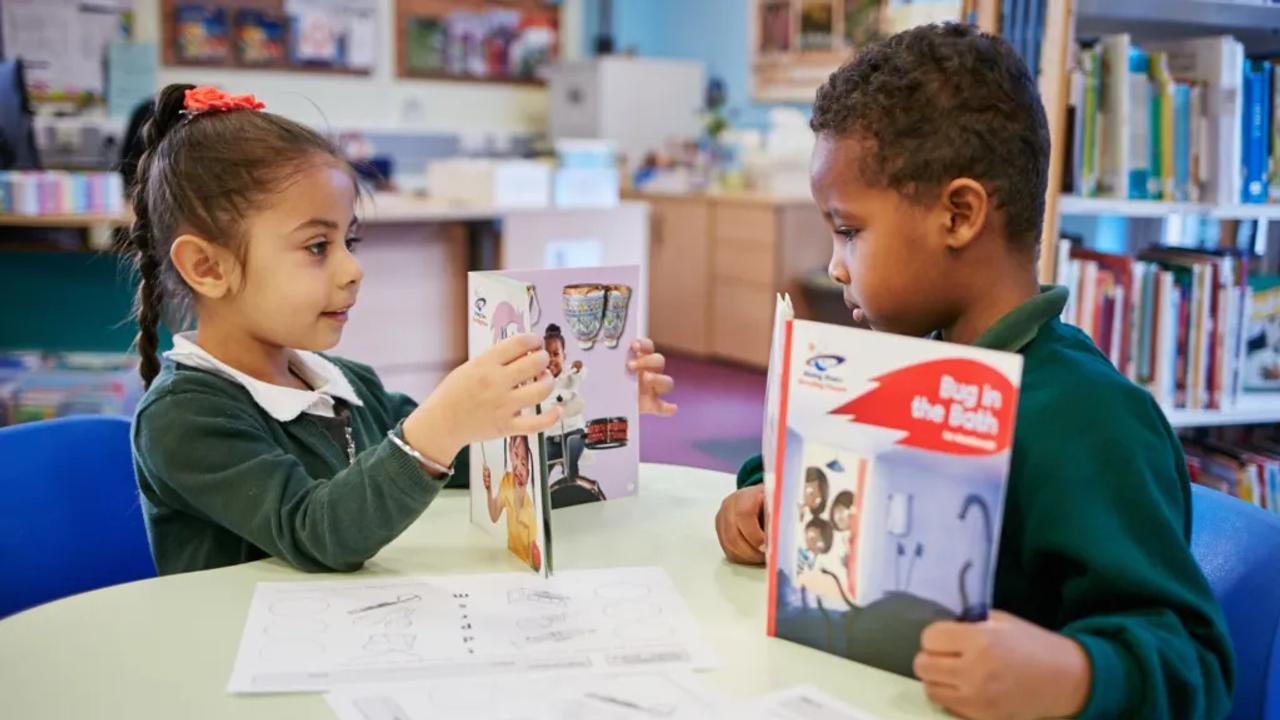 Two children sat at a table reading books