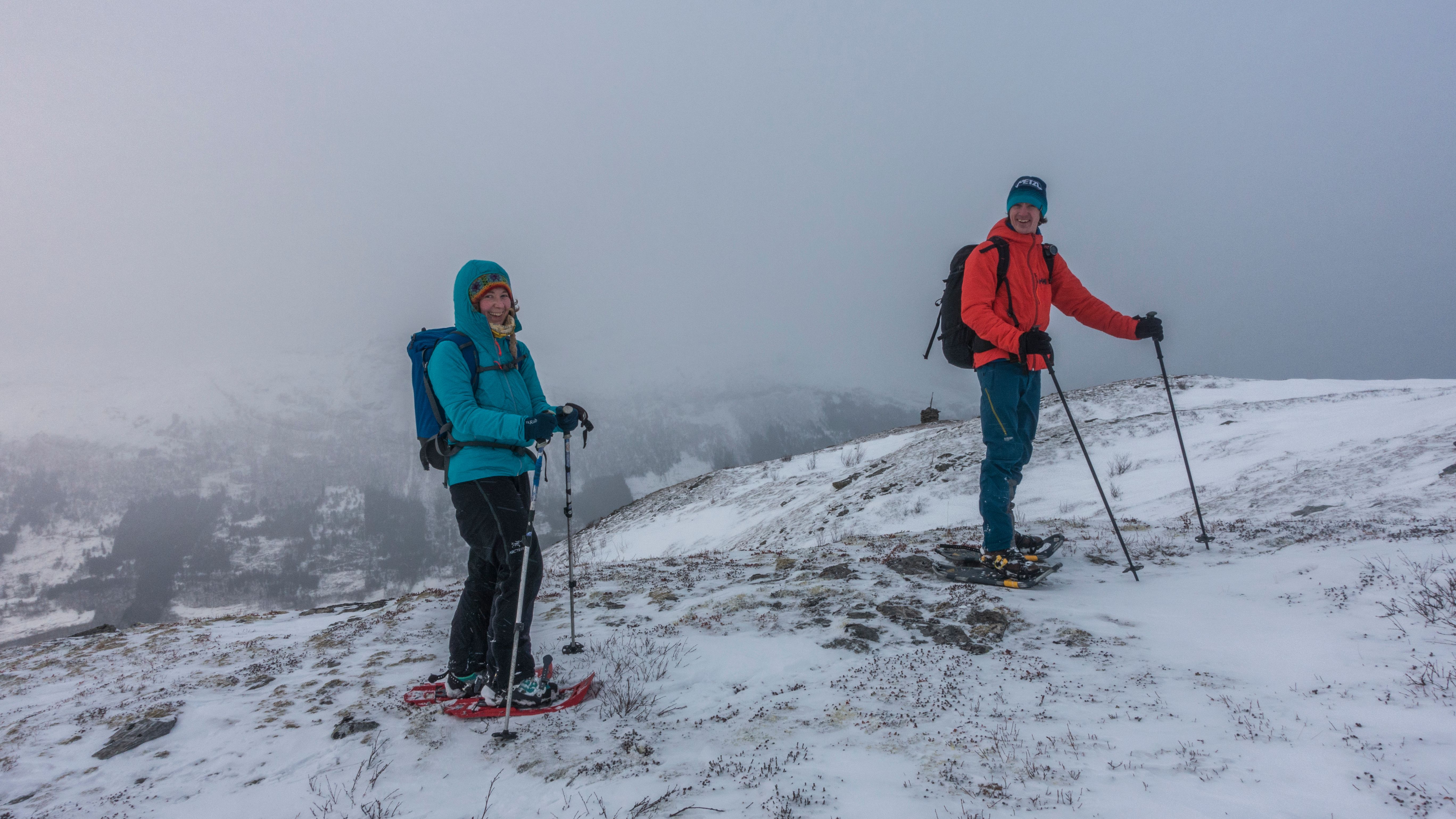 Snowshoers in wintry mist with mountains fading in the background.