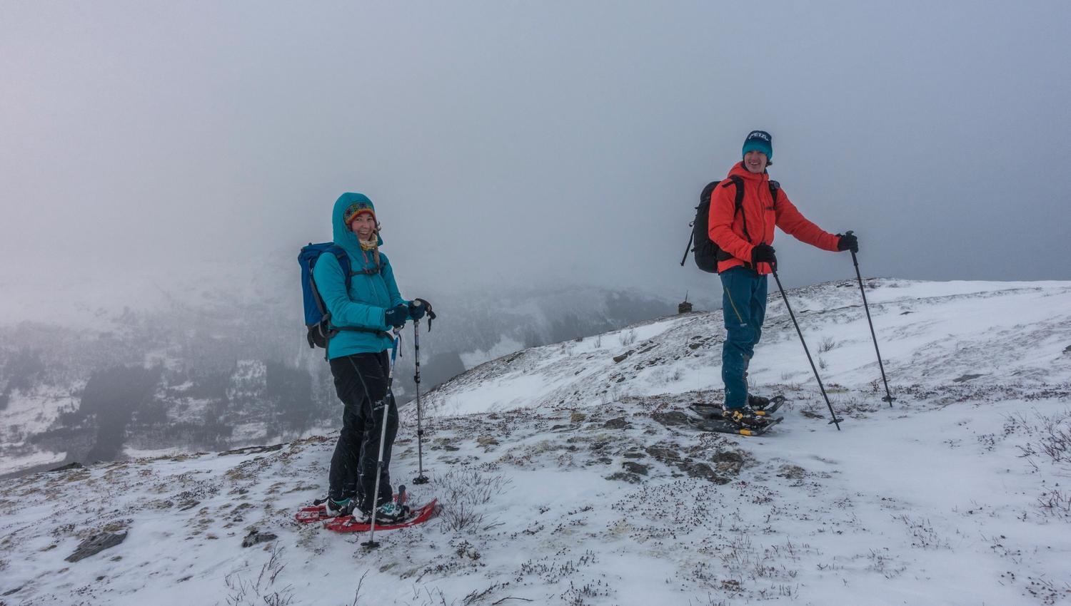 Snowshoers in wintry mist with mountains fading in the background.