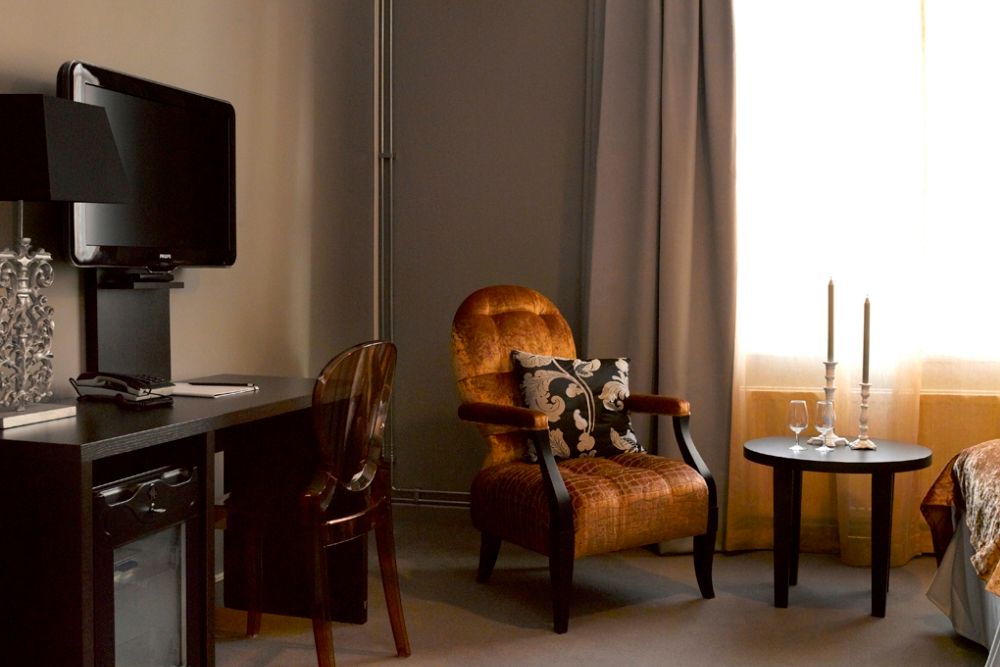 Stol og bord med lyslykt foran vindu- TV på veggen. Saga Hotel Oslo. Foto