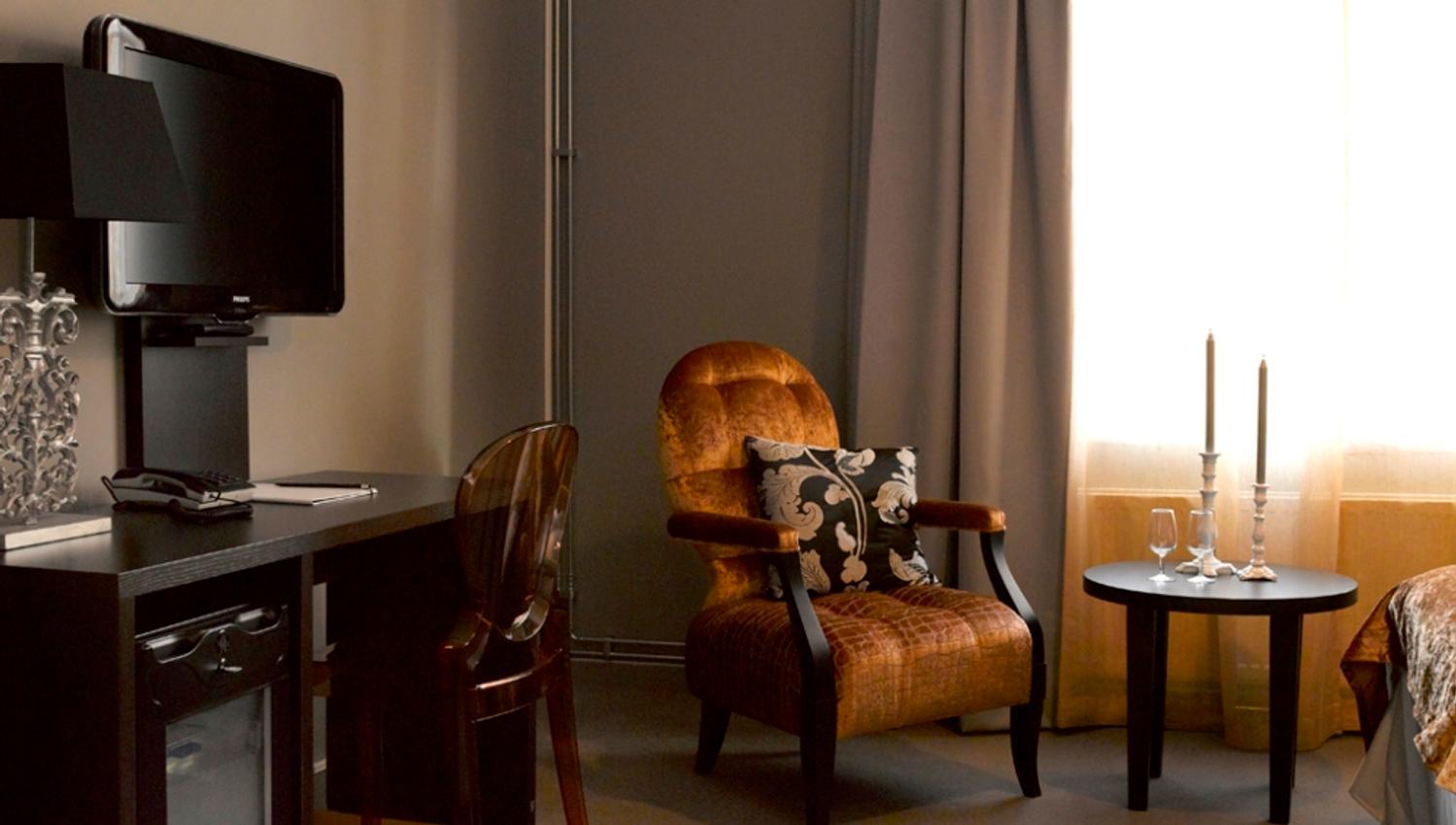 Stol og bord med lyslykt foran vindu- TV på veggen. Saga Hotel Oslo. Foto