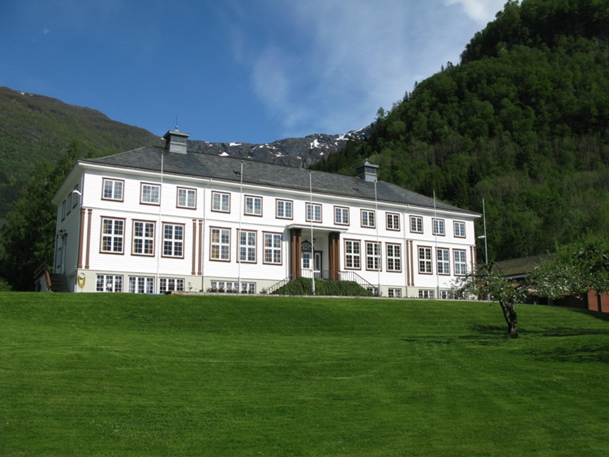 Hardanger Hostel B&B – sjarmerande kvit bygning omgitt av grøne lier og fjell i Hardanger.