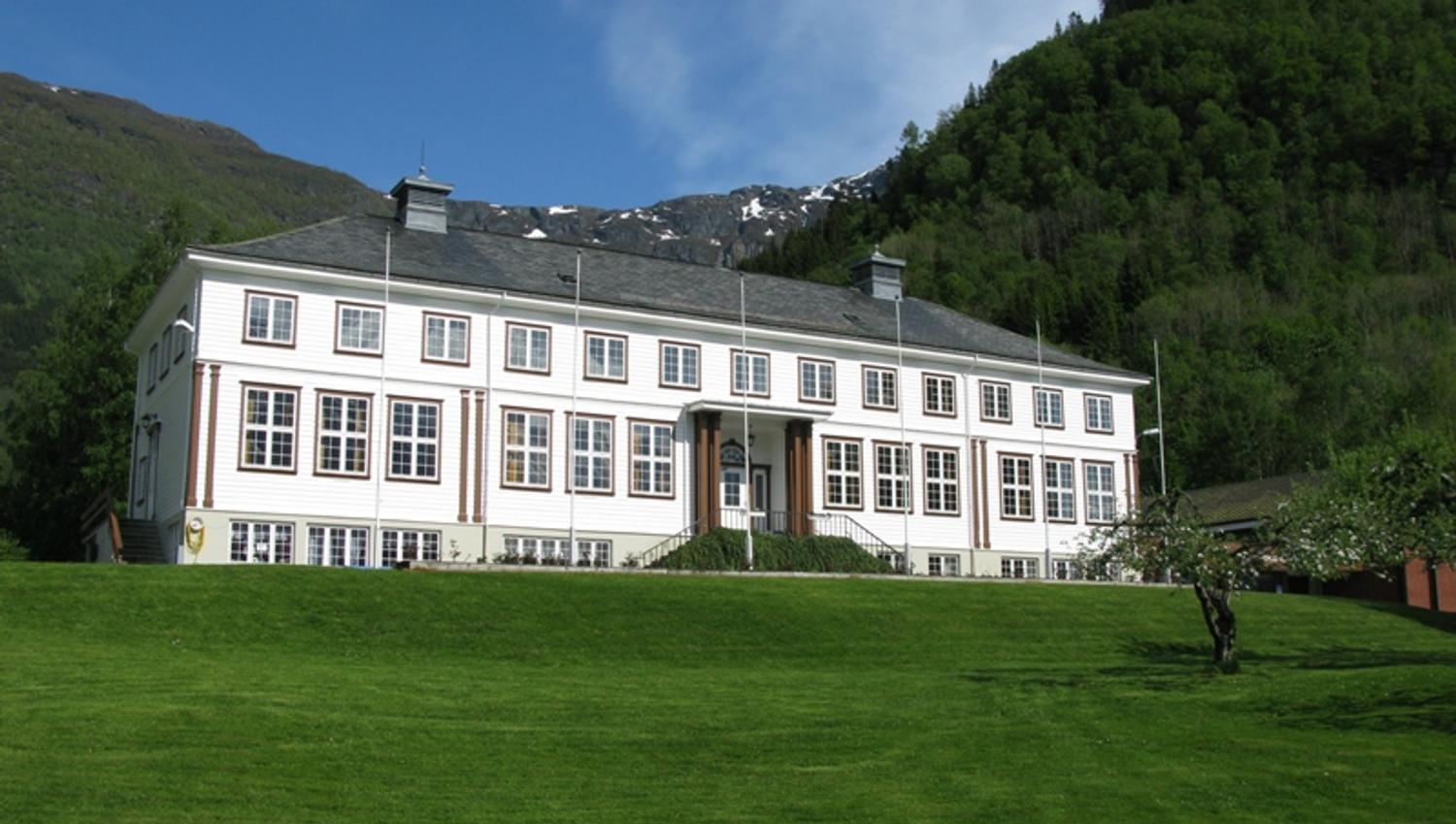 Hardanger Hostel B&B – sjarmerande kvit bygning omgitt av grøne lier og fjell i Hardanger.