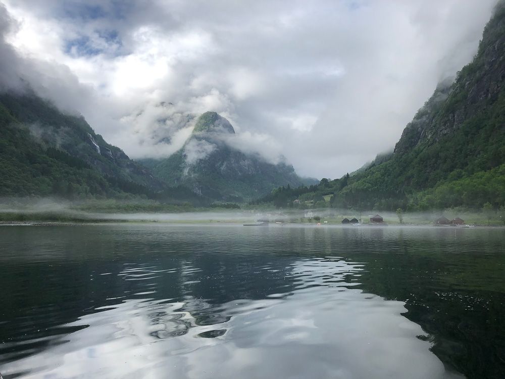 Magisk stemning i Hardangerfjorden med lav tåke som ligg over vatnet og fjella i bakgrunnen.