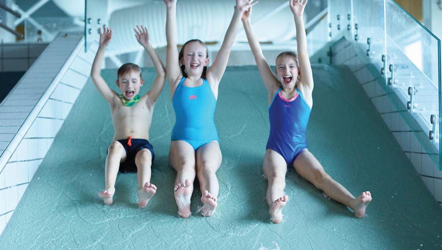 Sklie i Ankerskogen svømmehall. Tre glade barn