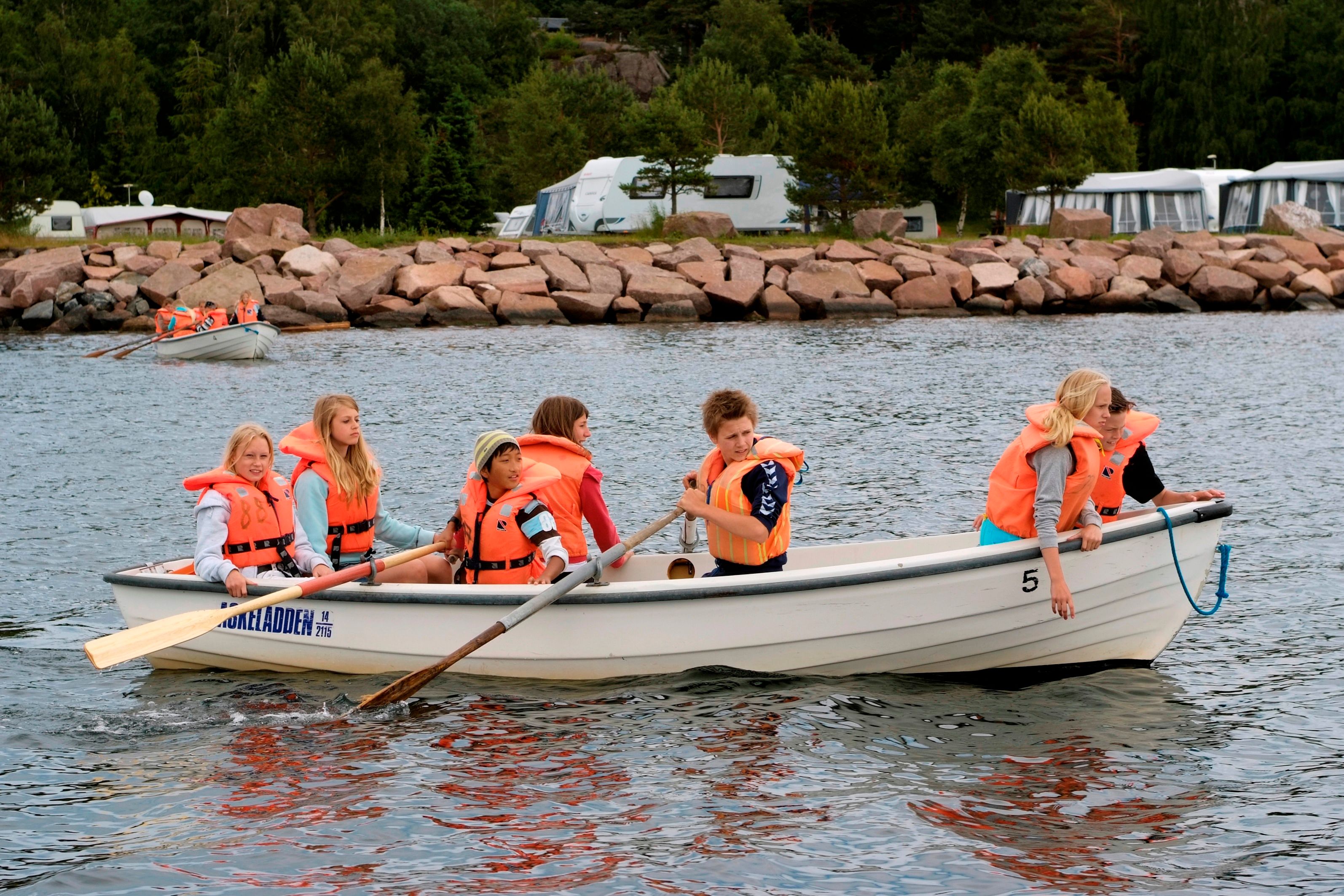 Barn som er ute i robåt på vannet utenfor campingplassen