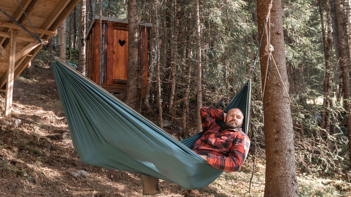 Man is lying in a hammock by a treetop iglo at Dalen