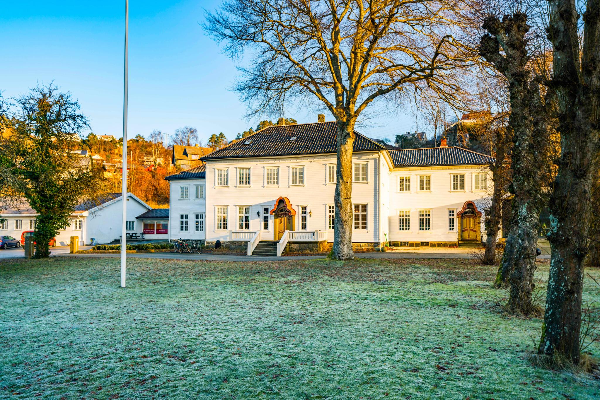 Hald Sommerhotell, en stor grønn flekk foran den hvite bygningen med mange vinduer,