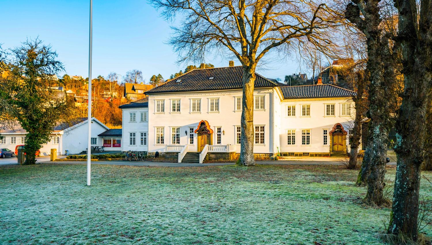 Hald Sommerhotell, en stor grønn flekk foran den hvite bygningen med mange vinduer,