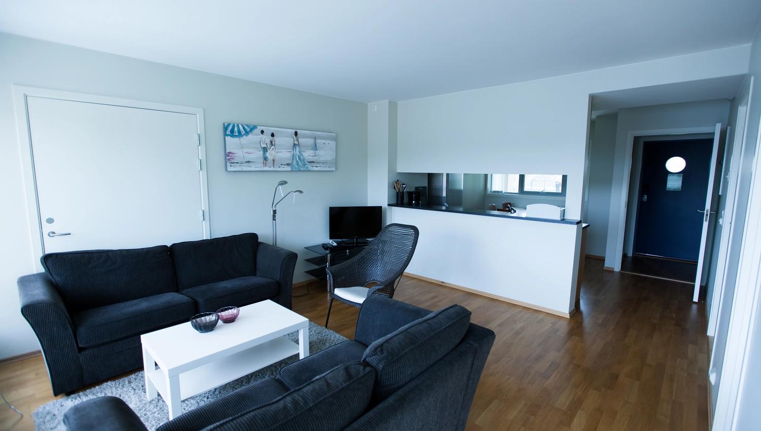 Lindesnes Havhotell – The living area of the hotel room, featuring a pair of black two-seater sofas.
