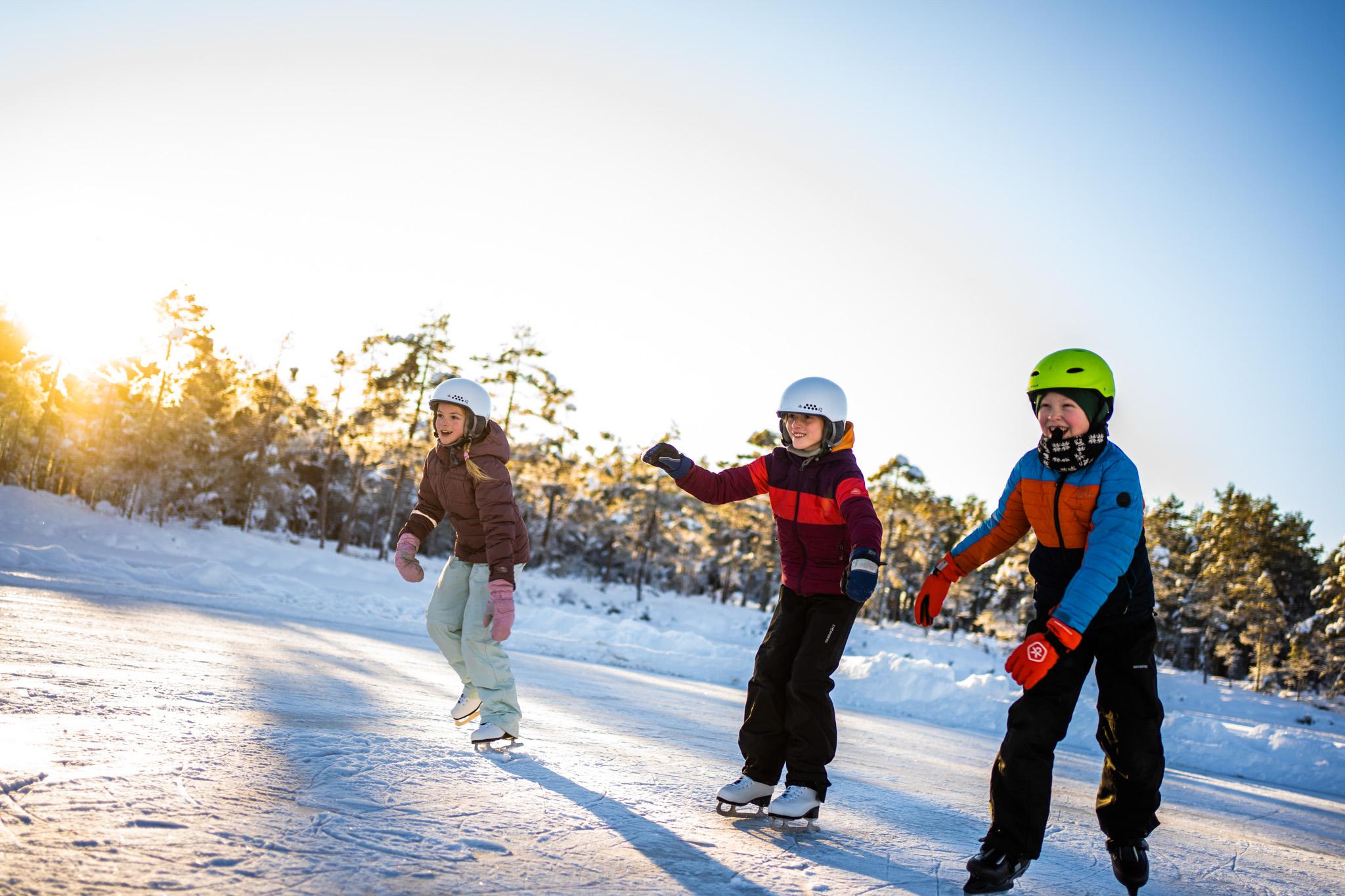 tre glade barn på skøytebanen