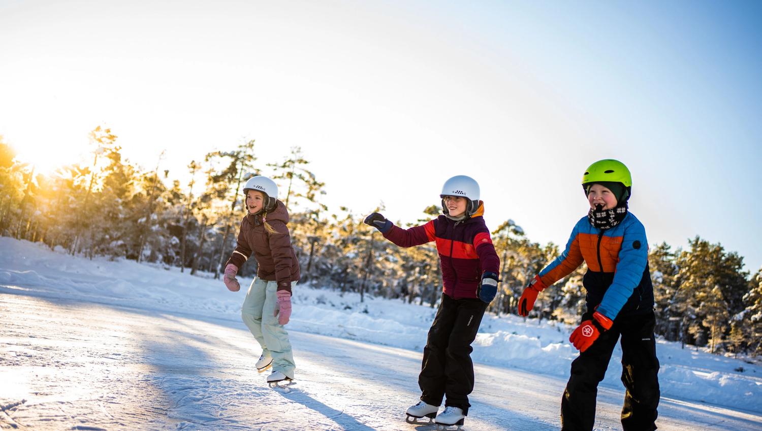 tre glade barn på skøytebanen
