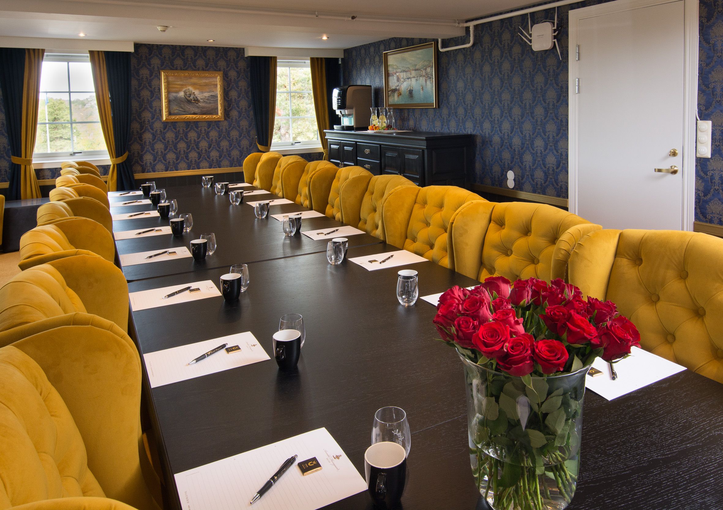 langt konferansebord dekket med penn og papir, kaffe og vannglass